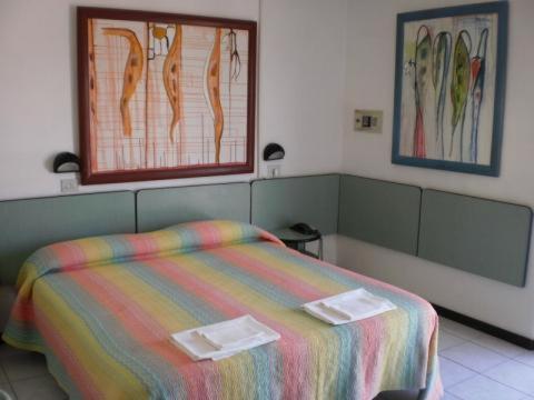 a bedroom with a bed with a colorful blanket at Hotel ristorante cavallino in Cesenatico