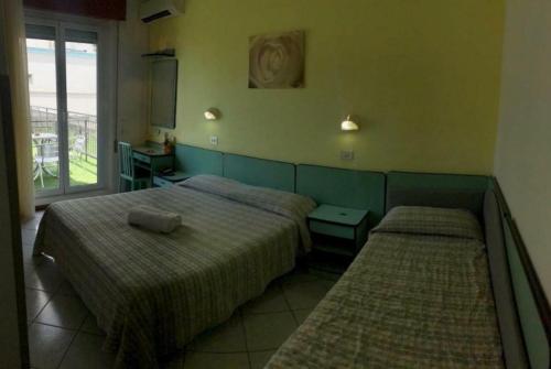 a bedroom with two beds and a window at Hotel ristorante cavallino in Cesenatico