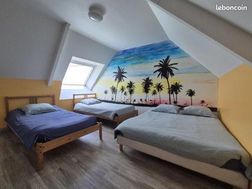 two beds in a room with a mural of palm trees at Gîte Le petit Fresnay in Le Bourgneuf-la-Forêt