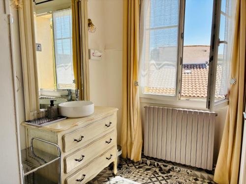 a bathroom with a sink and a mirror and a window at Hôtel Le Siècle in Mazan