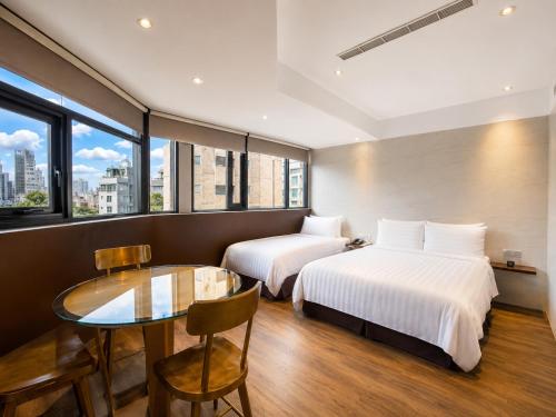 a hotel room with two beds and a glass table at Hotel Relax 5 in Taipei