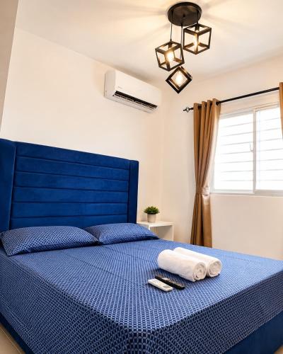 a bedroom with a blue bed with towels on it at Tropical Pearl Getaway in Los Paredones