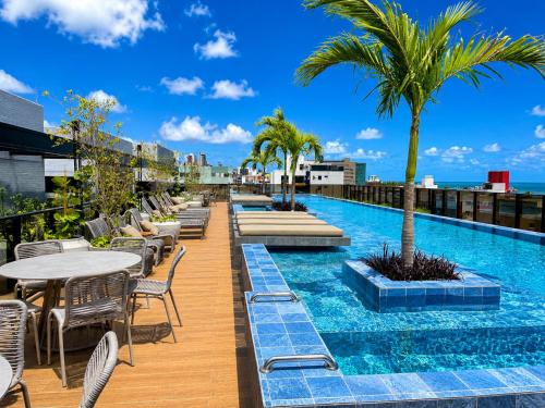 a pool on the roof of a building with tables and chairs at Hit Cabo Branco by 123Quarto in João Pessoa