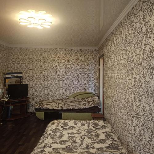 a bedroom with two beds in a room with wallpaper at Квартира in Sumy