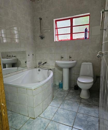 a bathroom with a tub and a toilet and a sink at Blessed home by the Mountain surrounded macadamia in Barberton