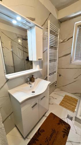 a white bathroom with a sink and a mirror at Guest House Bosnian House in Sarajevo