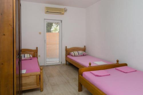 two beds in a room with pink sheets at Apartmani Šarkinović in Sutomore