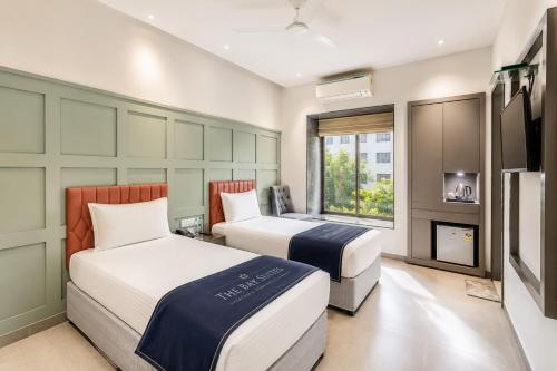 two beds in a room with a fireplace and a tv at The Bay Suites - Salt Lake in kolkata