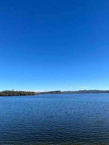 a large body of water with trees in the distance at Departamento de las sierras in Embalse