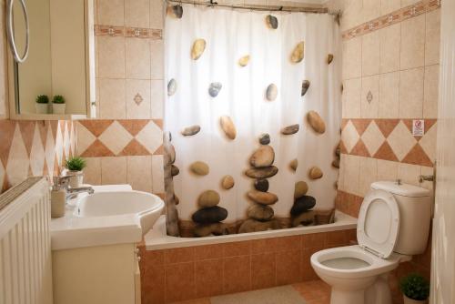 a bathroom with a toilet and a shower curtain with shells at Vasw Apartment in Ágios Nikólaos
