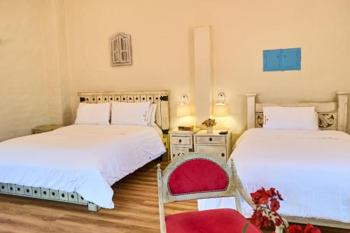two beds in a room with two chairs and a chair at Casa Provenzal Hotel Boutique in Villa de Leyva