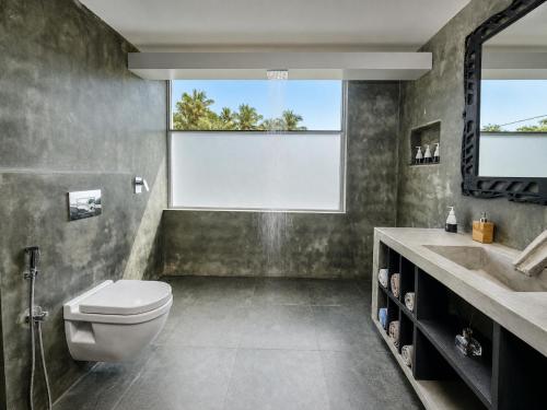 a bathroom with a toilet and a sink and a window at Waterland in Negombo