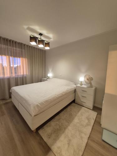 a white bedroom with a bed and a window at Boose Apart in Kobela