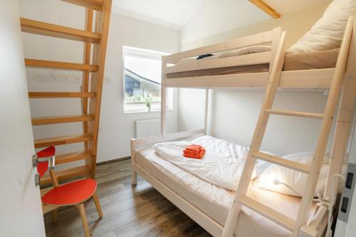 a small room with bunk beds and a chair at Haus JADEHUUS in Schweiburg