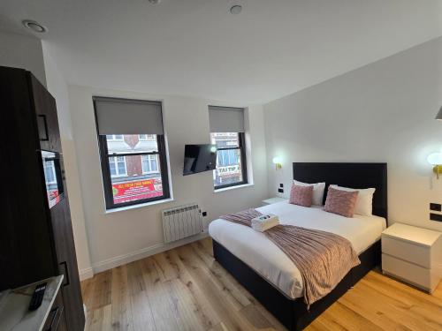 a bedroom with a large bed and two windows at Ash Tree Hotel in Woolwich