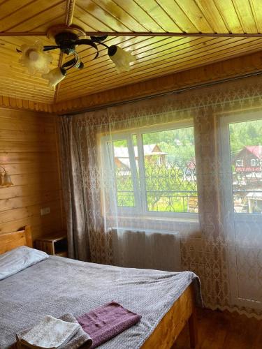 a bedroom with a bed and two windows and a ceiling at TaVa House 2 in Yaremche
