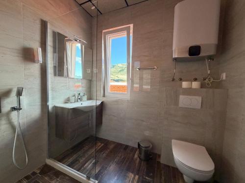 a bathroom with a toilet and a sink and a window at Apartments Memories EV ch 11kW available in Trebinje
