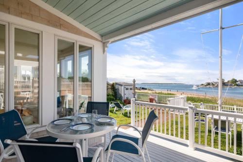 a porch with a table and chairs and a view of the ocean at Waterfront Private Beach Gorgeous Views in Yarmouth