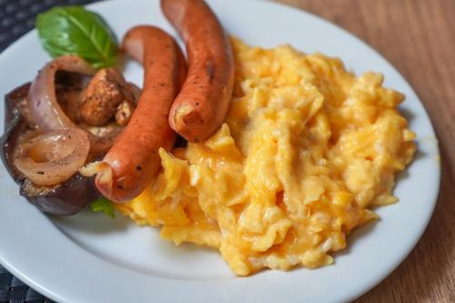 a plate of food with eggs and sausages and mushrooms at Penzión Ingrid in Štrbské Pleso