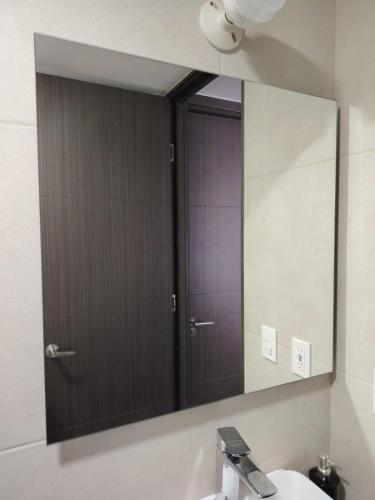 a bathroom mirror with a door and a sink at Bostor Apartament in San Salvador