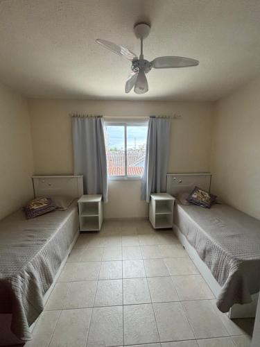 a bedroom with two beds and a ceiling fan at Sobrado confortável a uma quadra do mar. in Matinhos