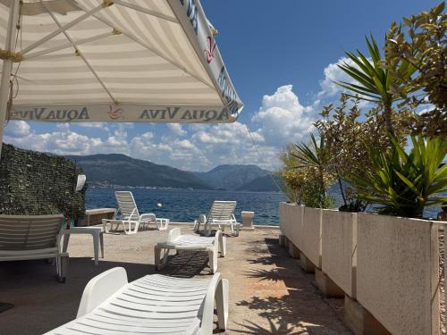 a row of chairs and umbrellas next to the water at Zo-Mi Apartments in Tivat