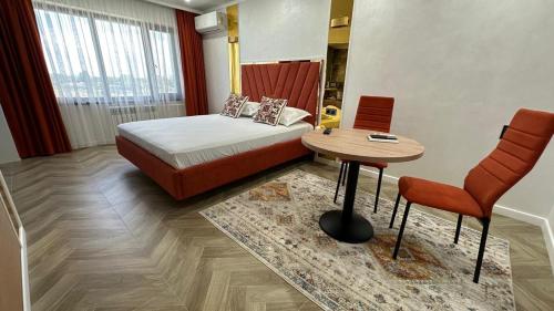 a bedroom with a bed and a table and chairs at Yuzhnaya in Qyzylorda