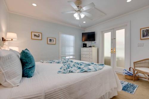 a bedroom with a white bed with a ceiling fan at Turtle Nest Condo - Pool - 2nd Floor in Key West