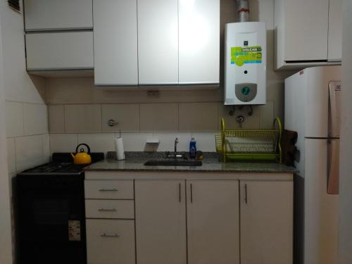 a kitchen with white cabinets and a sink and a refrigerator at Casa Estadio con cochera in Santiago del Estero
