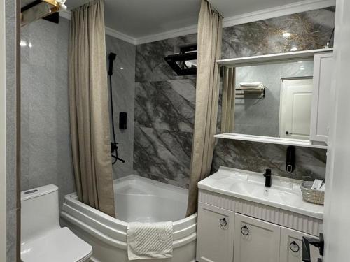 a bathroom with a toilet and a tub and a sink at Yuzhnaya in Qyzylorda