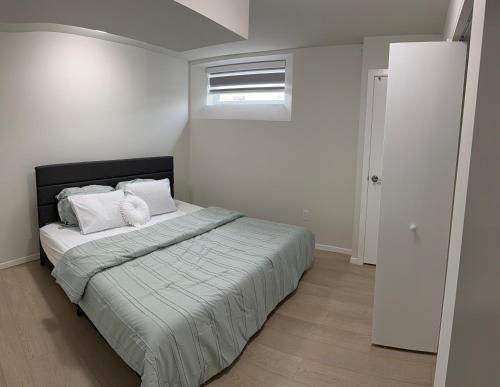 a bedroom with a bed with white sheets and a window at Dans luxury suite in Winnipeg