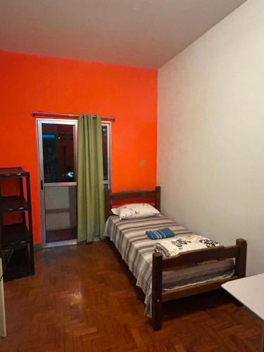 a bedroom with orange walls and a bed in it at Hostel Vergueiro in São Paulo