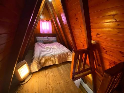 a small bedroom with a bed in a wooden cabin at Chalé - Sossego 1 in Campos do Jordão