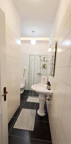 a white bathroom with a sink and a toilet at Marina Chic Apartment in Vlorë