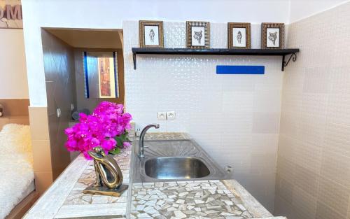 a bathroom sink with a vase of flowers on a counter at Hébergement H in Ngaring