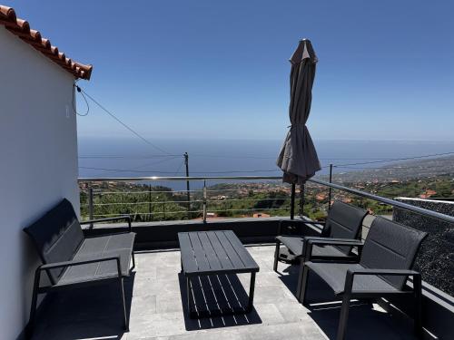 a balcony with a table and chairs and an umbrella at Hiking & Ocean in Arco da Calheta