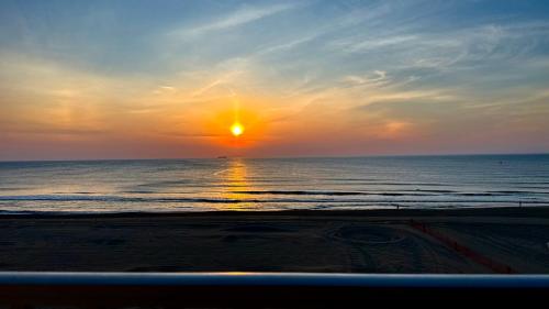 a sunset on the beach with the sun setting at Boardwalk Oceanfront Condo with Panoramic Views in Virginia Beach