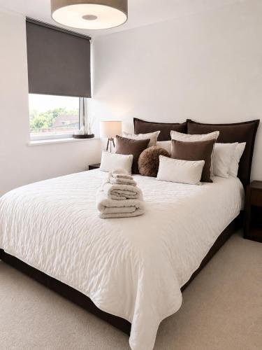 a bedroom with a large white bed with towels on it at Luxury Central Solihull Apt - King Bed, Sofa Bed & 2 Parking Spaces in Solihull