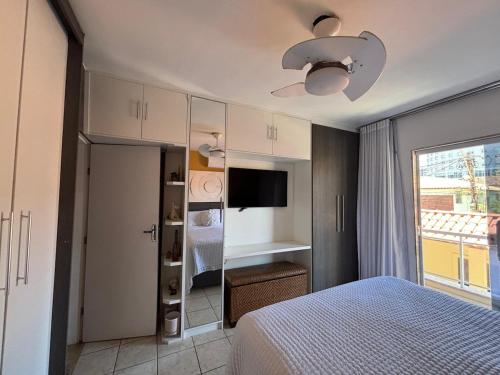 a bedroom with a bed and a tv and a window at Casa Costa do Sol completa, 100m da praia in Macaé