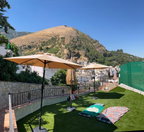a patio with two umbrellas and a mountain at Casa Angel in Cazorla