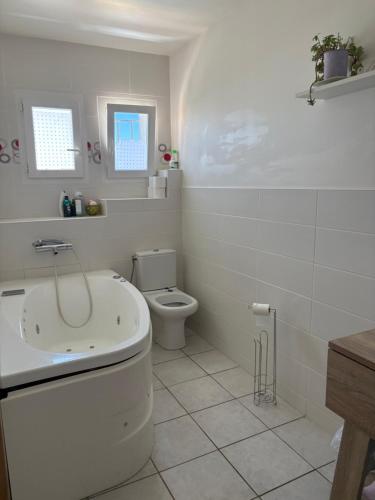 a white bathroom with a toilet and a sink at Villa playa in Valras-Plage