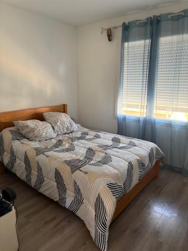 a bedroom with a bed and a window with blue curtains at Villa playa in Valras-Plage