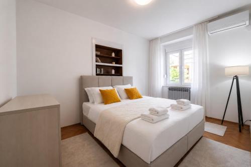 a white bedroom with a large bed with towels on it at Maison Des Oliviers in Herceg-Novi