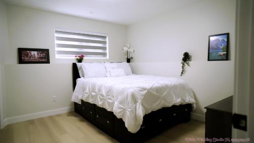 a bedroom with a bed with white sheets and a window at The Ivory house in Prince George