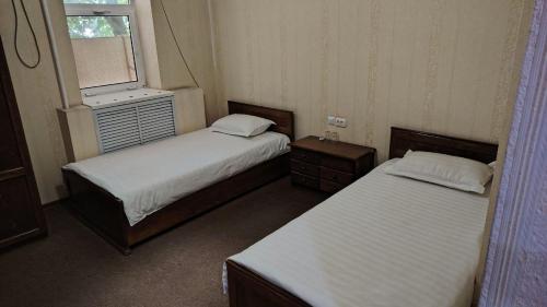 two beds in a small room with a window at Comfort Continent in Oktyabrʼ
