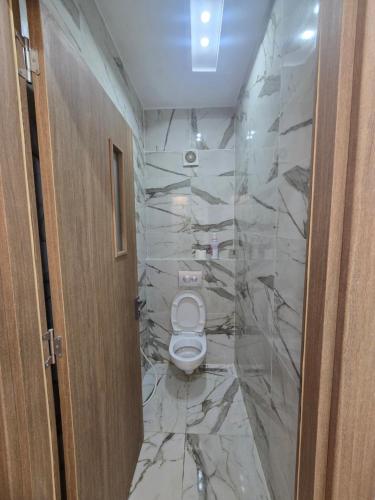 a bathroom with a toilet and a marble wall at Apparemment valmascort annaba in Annaba