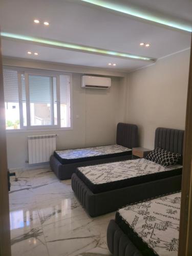 a room with three beds and a window at Apparemment valmascort annaba in Annaba