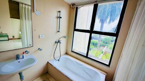 a bathroom with a sink and a tub and a window at Tranquil villa Raichak in Diamond Harbour