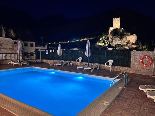 a swimming pool with chairs and umbrellas at night at Casa Tio Paco in Cazorla