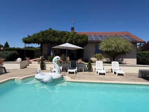 a swimming pool with an inflatable swan and chairs at L'Esprit Cottage in La Tranclière